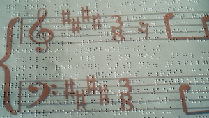An embossed grand stave superimposed over Braille notation